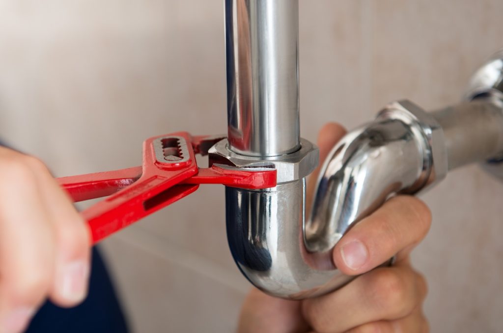 Plumber fixing a pipe with a wrench