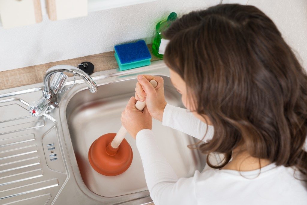 Woman using a plunger for the kitchen sink