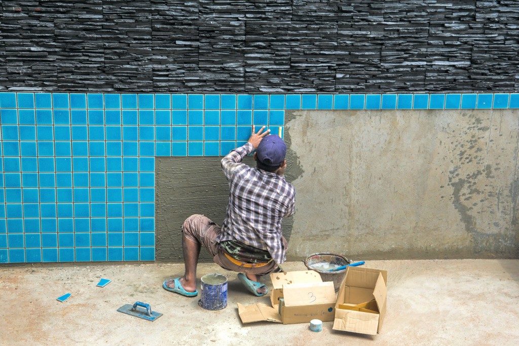 man applying pool tiles