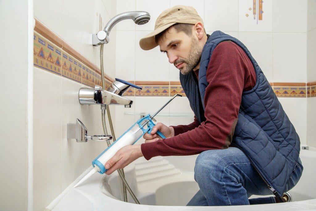 Worker applying sealant on the bathtub