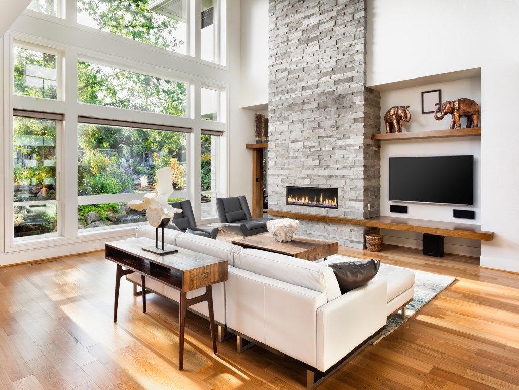living room with a glass window, in a wood flooring, cream sofa, and fireplace