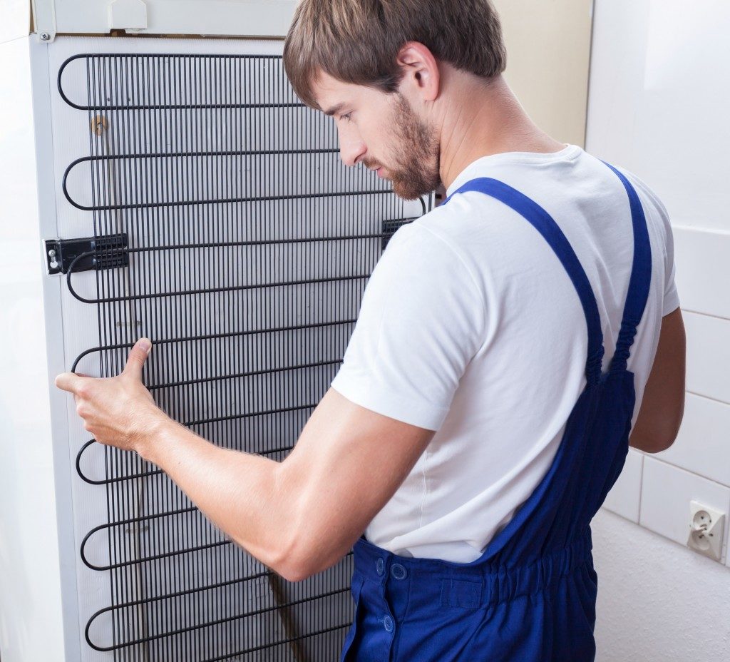 man fixing the back of a fridge