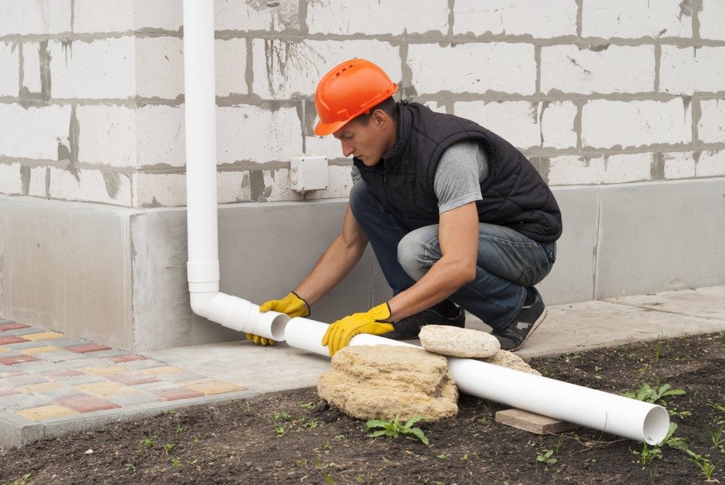man installing an exterior drainage outside a house