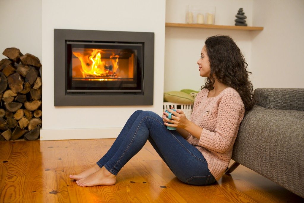 woman relaxing with a mug of tea in the living room near the fireplace with door