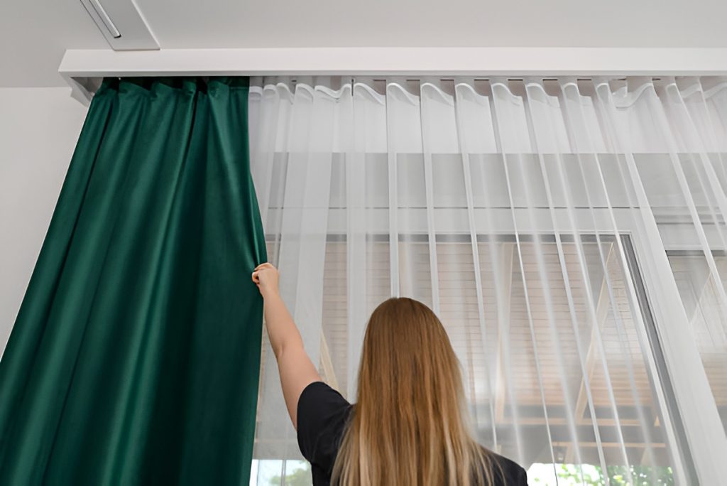 woman closing blackout curtains over sheer curtains